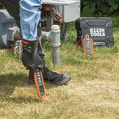 Person using a device on grass with Klein Tools equipment in the background