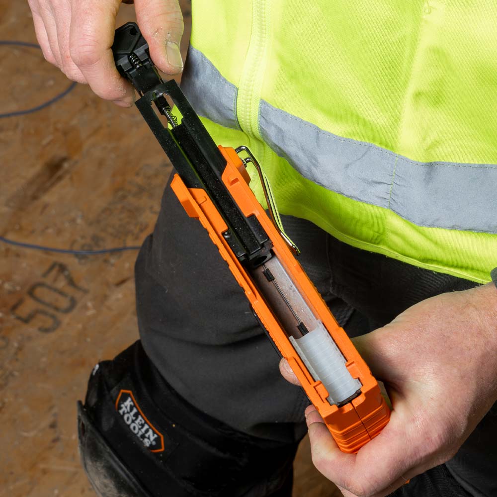 Person holding a tool with a high-visibility vest in the background