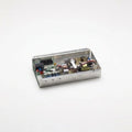 A small rectangular metal electronic control box with its lid open, showing internal circuitry, capacitors, and wires, set against a plain white background.