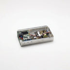 A small rectangular metal electronic control box with its lid open, showing internal circuitry, capacitors, and wires, set against a plain white background.