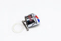 A small chrome metal car emblem or badge with red and blue accents, shown on a plain white background next to a white circular washer or gasket.