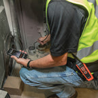 Person in high-visibility vest using a smartphone in an industrial setting