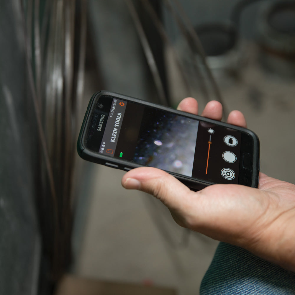 Person holding a smartphone with a screen displaying a tool app.