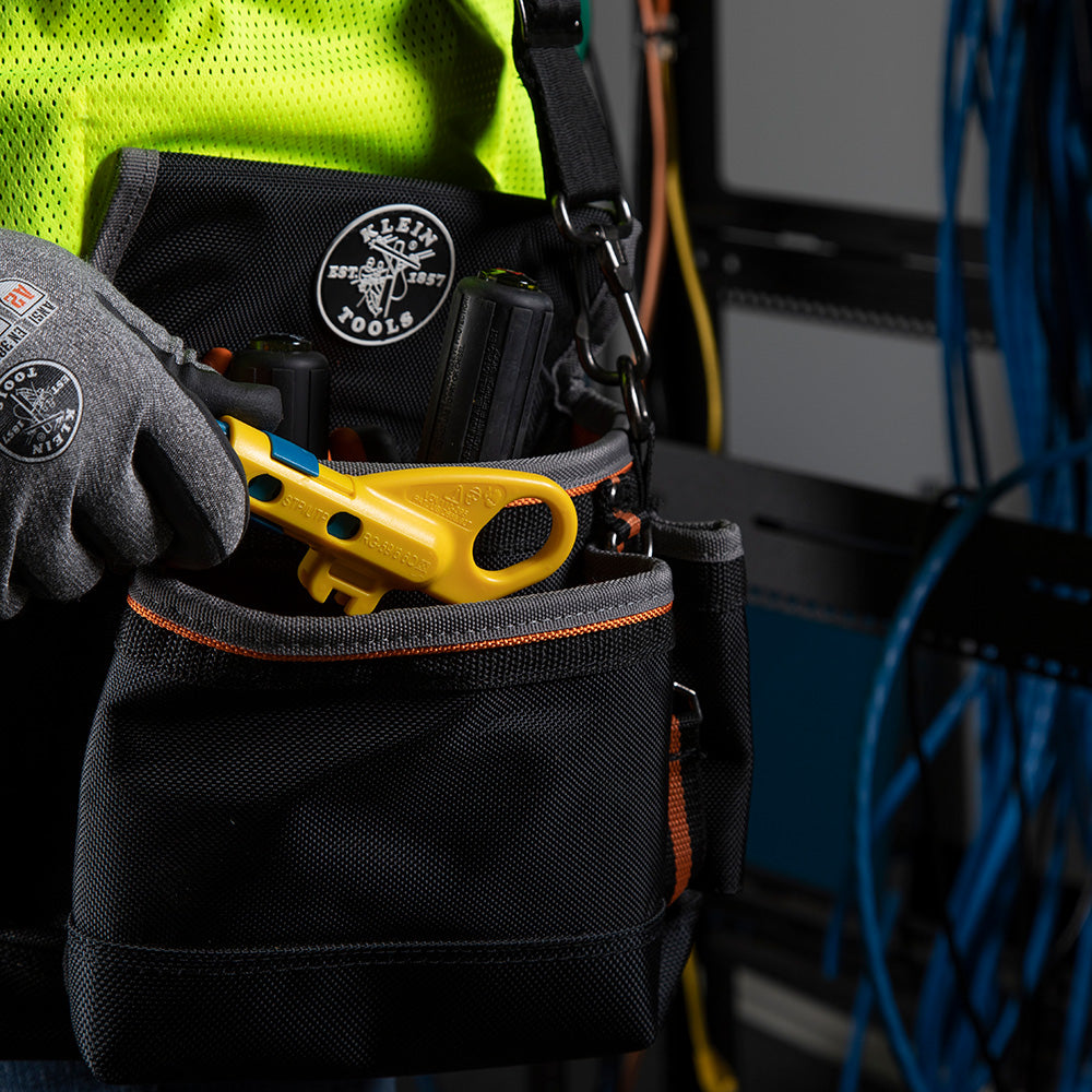 Black tool pouch with yellow tool and gloves on a blurred background