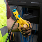 Person wearing a high-visibility vest and gloves holding a yellow tool with blue accents.
