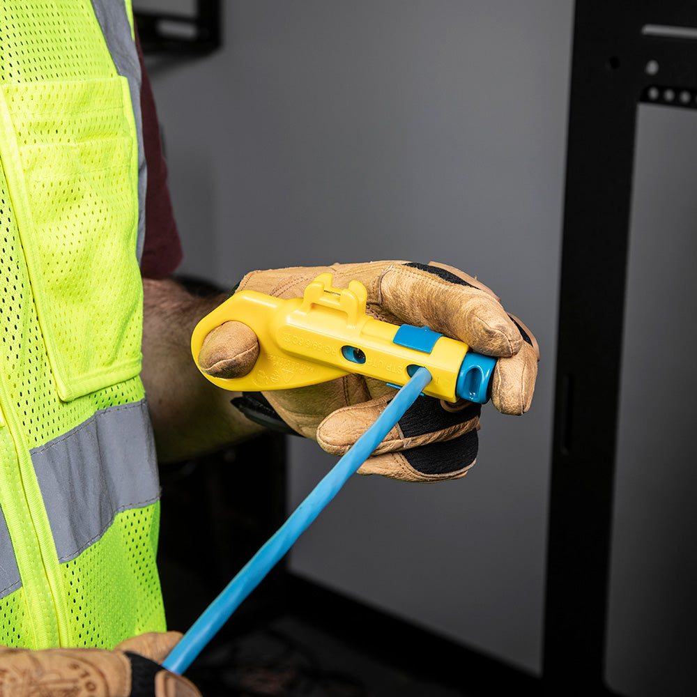 Person wearing a high-visibility safety vest and gloves holding a yellow tool with a blue handle.