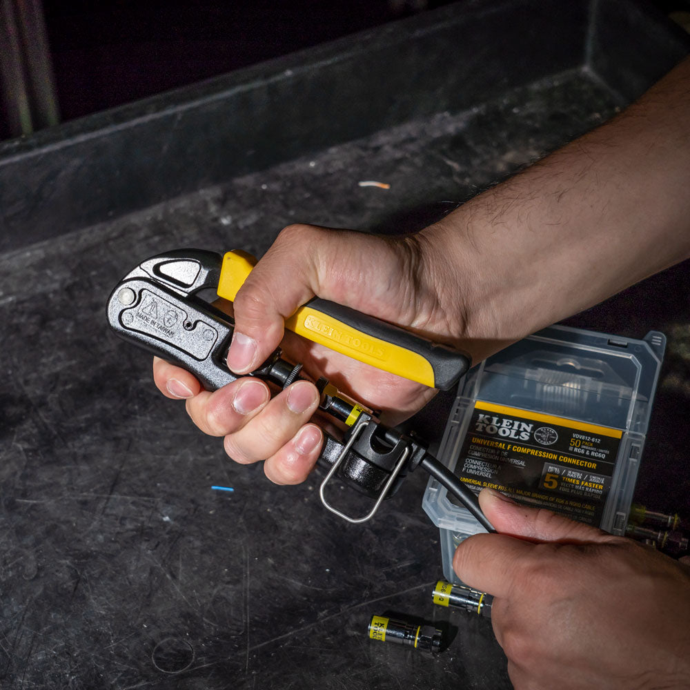 Person using Klein Tools cable crimping tool on a dark surface