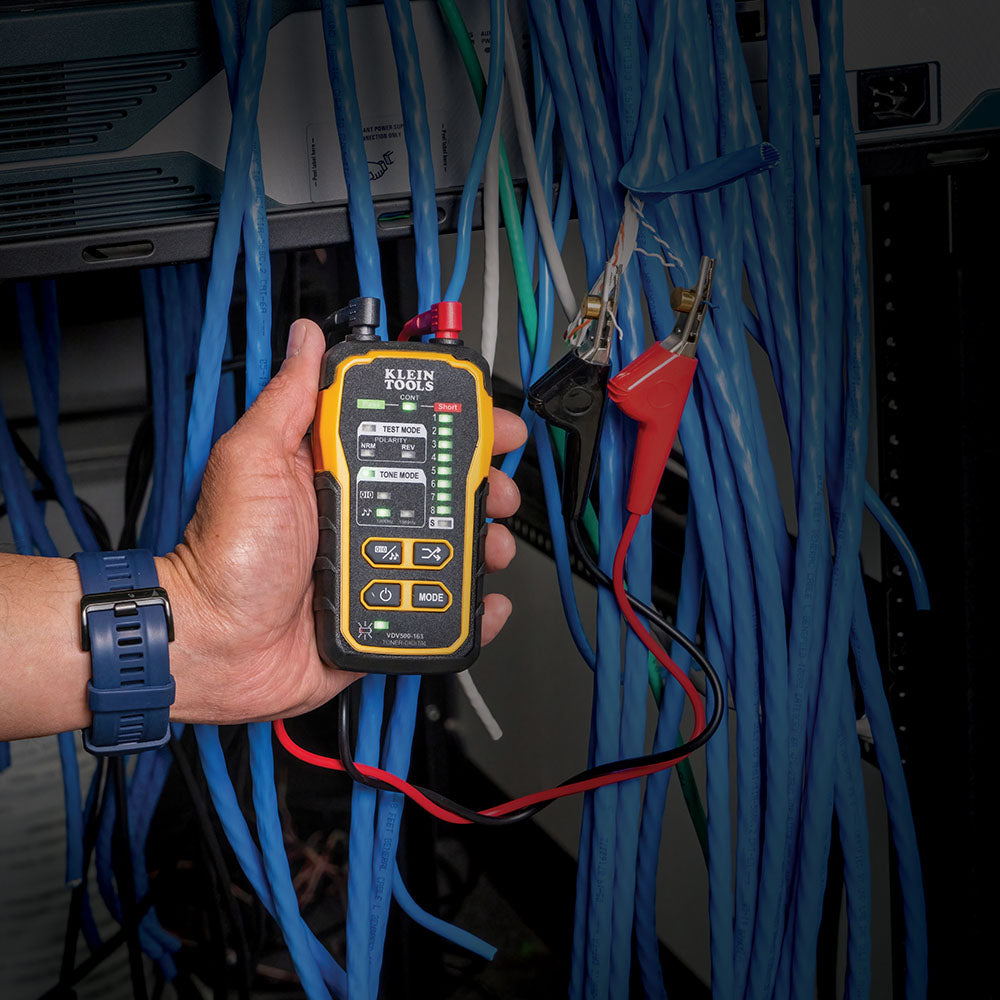 Person holding a network cable tester among blue cables in a technical setting