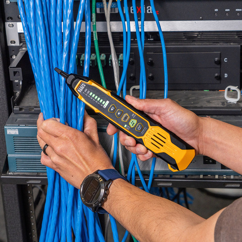 Person using a network cable tester in a server room with blue cables.