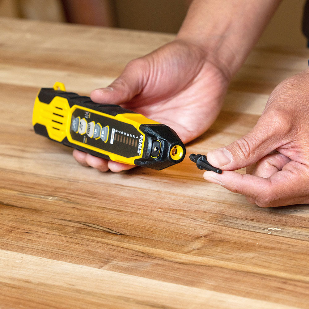 Person using a yellow and black tool on a wooden surface